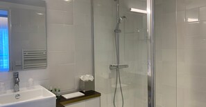 Une salle de bain moderne avec une douche à parois de verre, un lavabo blanc et un miroir.