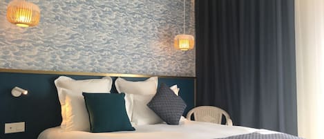 A hotel room with a bed, pillows, a nightstand, and a wall with a textured pattern.