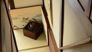 A traditional Japanese room with tatami flooring, a low wooden table with a teapot, and a shoji screen with a landscape painting. - Nishioji Tanuki (Kyoto)
