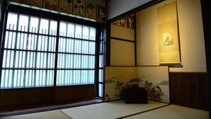 A traditional Japanese room with tatami flooring, shoji screens, and artwork on the walls. - Nishioji Tanuki (Kyoto)