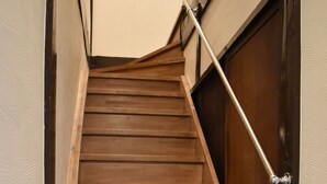 A wooden staircase with a metal handrail leading to a closed door. - Nishioji Fukuro (Kyoto)