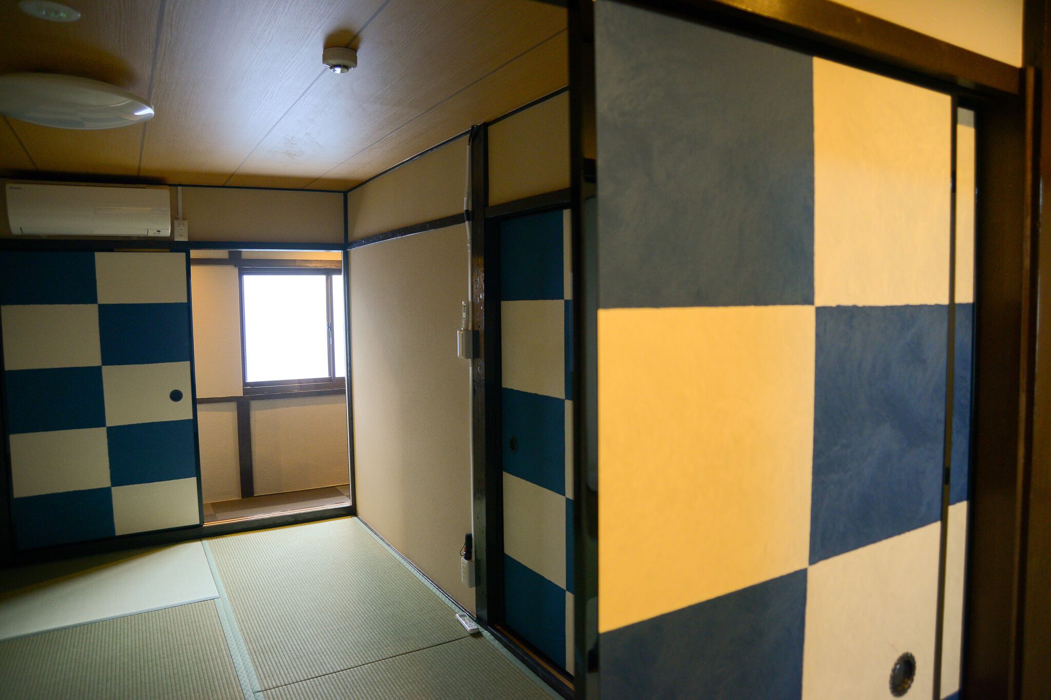 A traditional Japanese room with tatami flooring, shoji screens, and a sliding door.