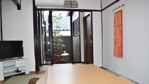 A bedroom with a bed, a TV, a desk, and a sliding door leading to a balcony. - Nishioji Fukuro (Kyoto)