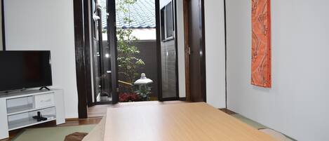 A bedroom with a bed, a TV, a desk, and a sliding door leading to a balcony.