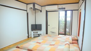 A bedroom with a large bed, a TV, and a sliding glass door to a balcony. - Nishioji Fukuro (Kyoto)