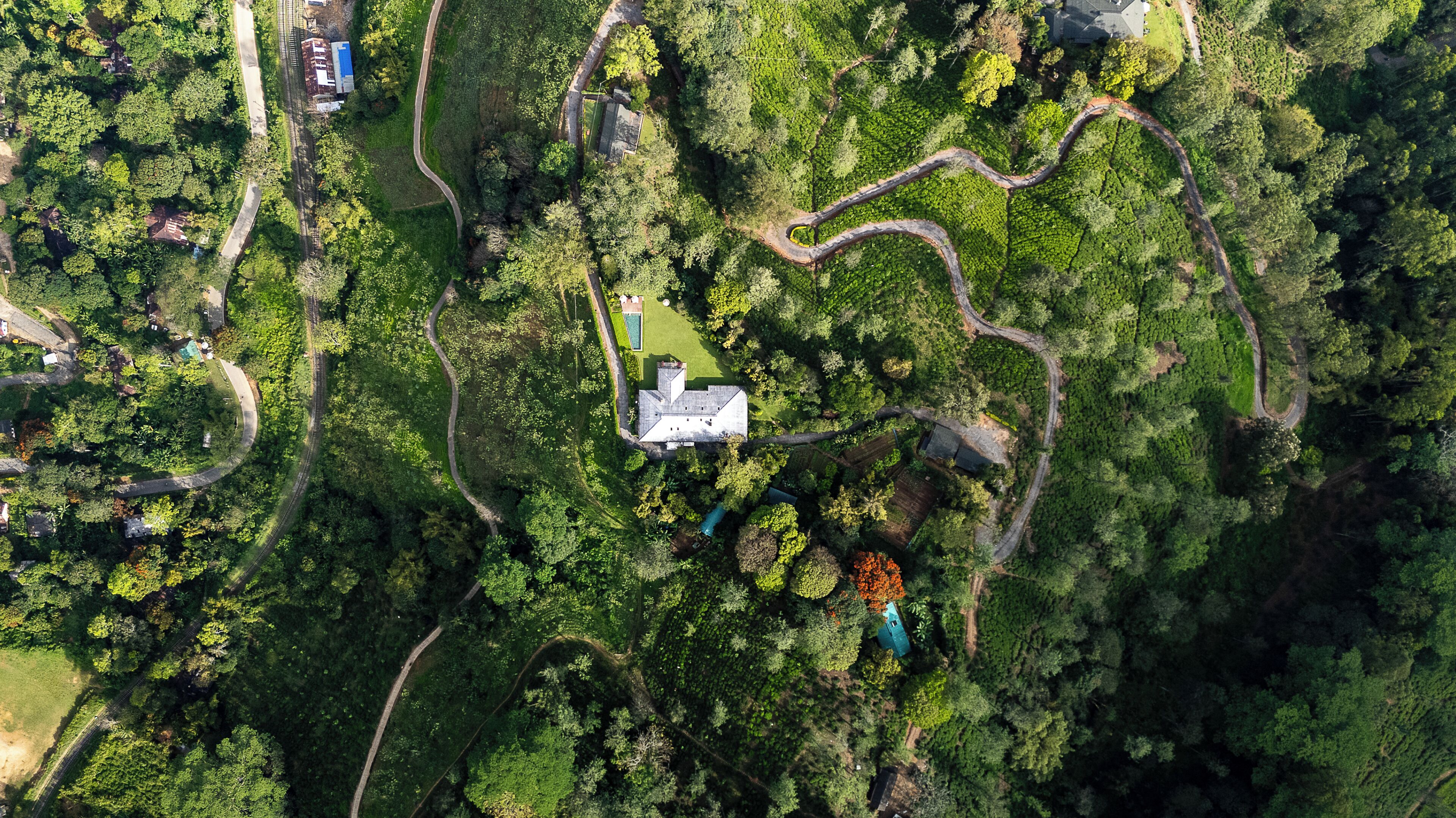 Vista aérea de una propiedad con caminos sinuosos, un edificio central y abundante vegetación.