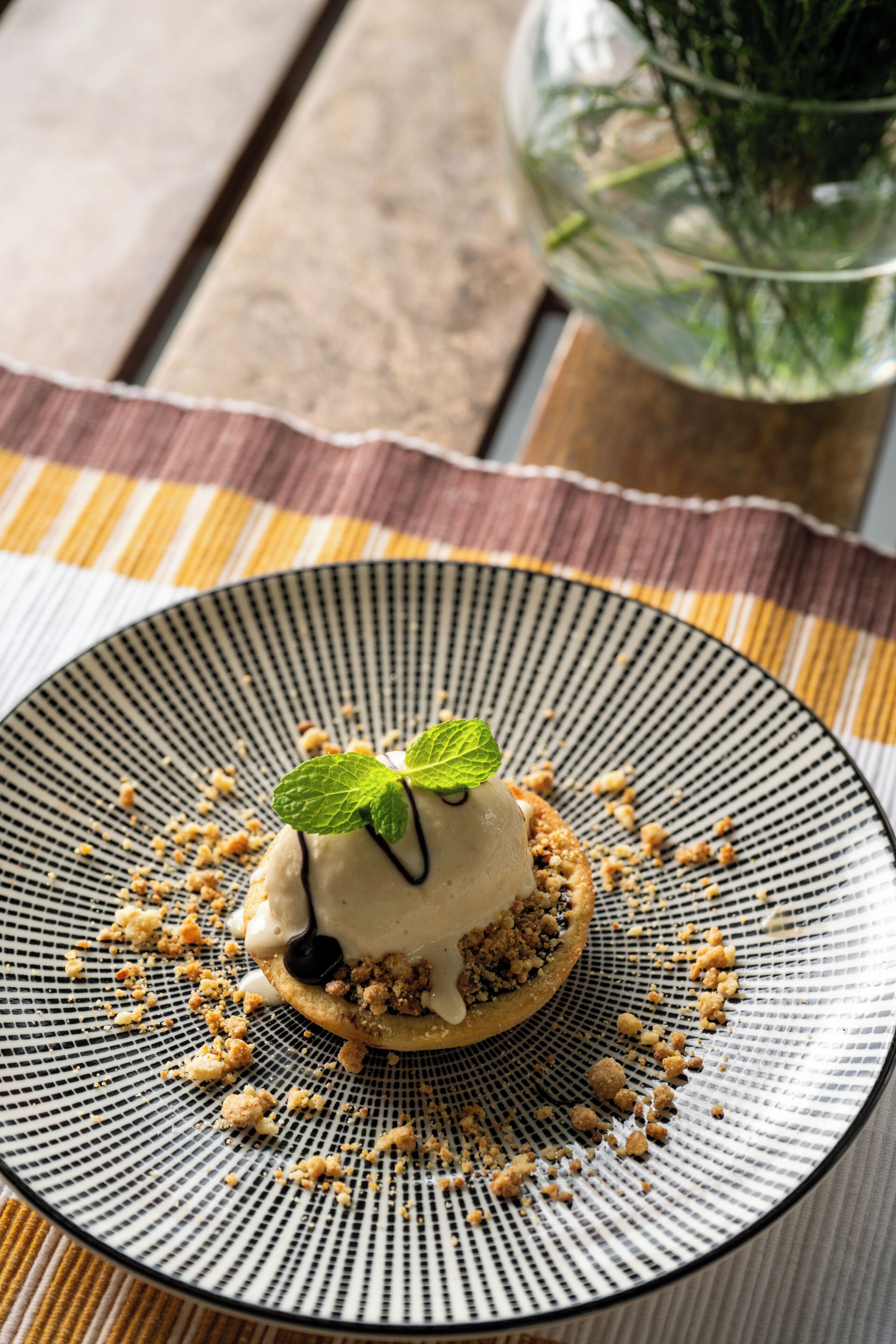A dessert on a plate with a mint leaf garnish, placed on a table with a striped placemat.