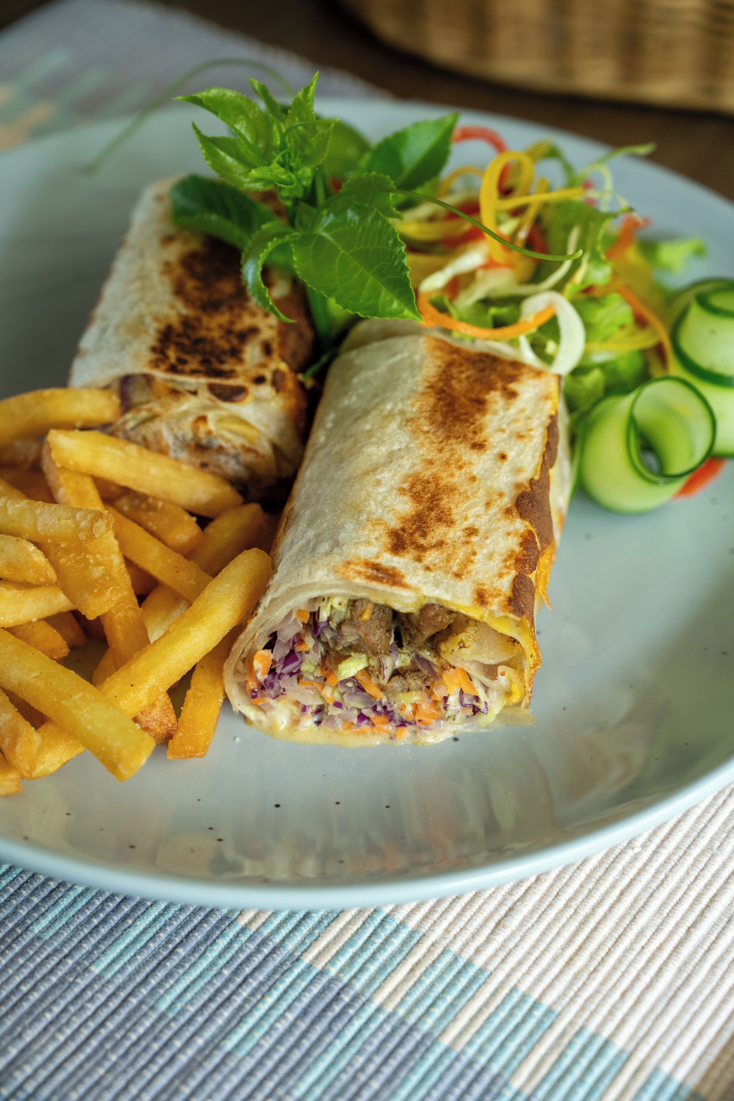 Une assiette comprenant un wrap, des frites et une salade.