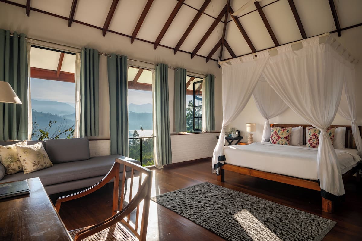 Ein Schlafzimmer mit Bett, einer Couch, einem Holztisch und Blick auf die Berge.