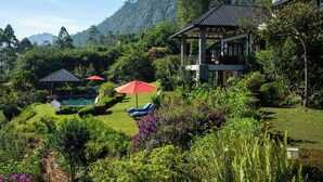 Um jardim exuberante com piscina, espreguiçadeiras e um gazebo.