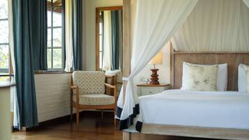 A bedroom with a wooden bed, a chair, a bedside table, and a window with curtains.