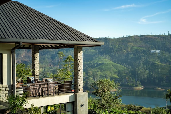 A modern building with a balcony overlooking a lake and hills.