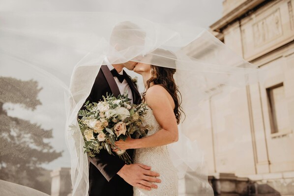A couple embracing under a veil, with a building in the background. - Lalloudes Mani Hotel (East Mani)