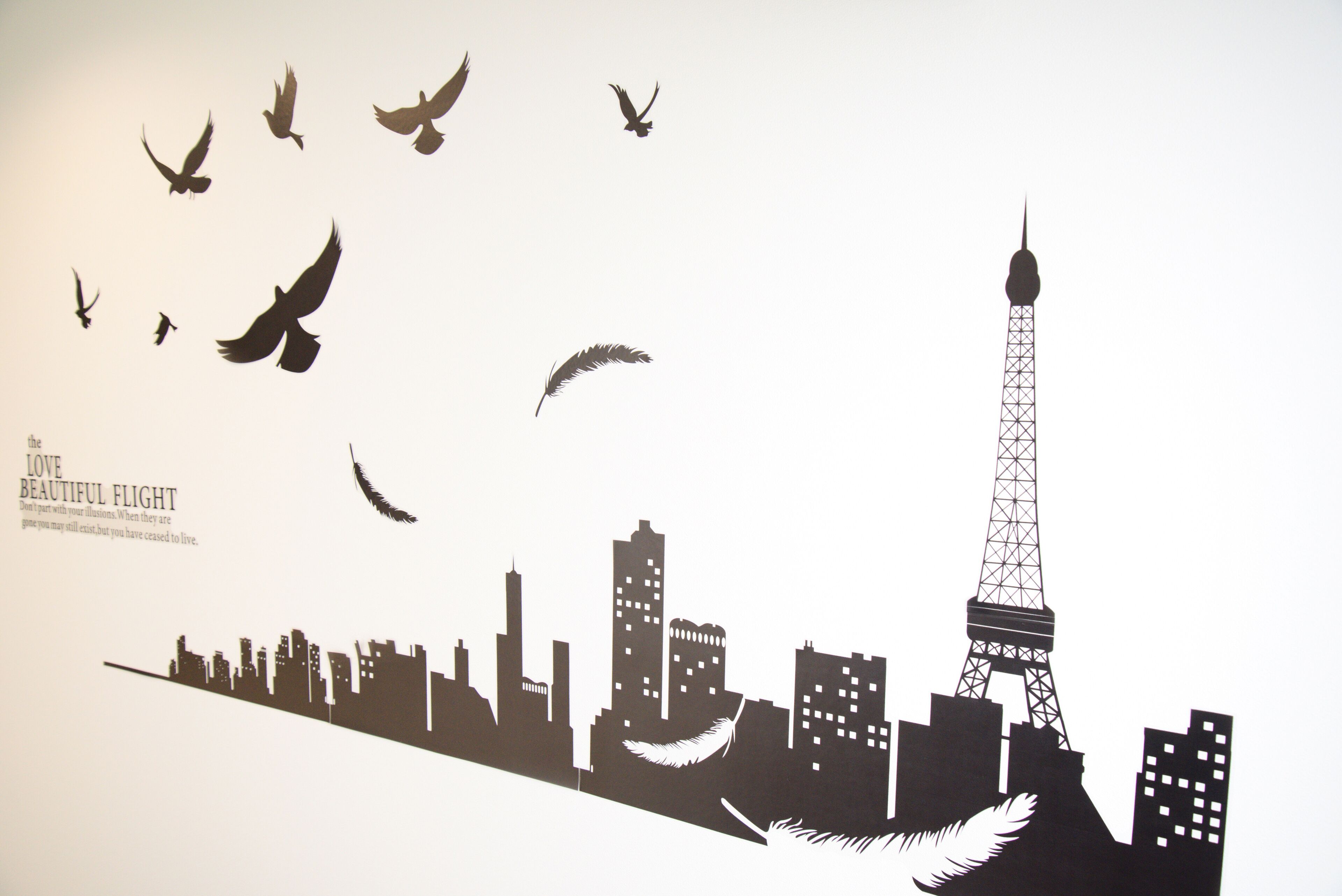 Silueta de un horizonte urbano con una torre destacada, probablemente la Torre Eiffel, y una bandada de pájaros volando por encima.