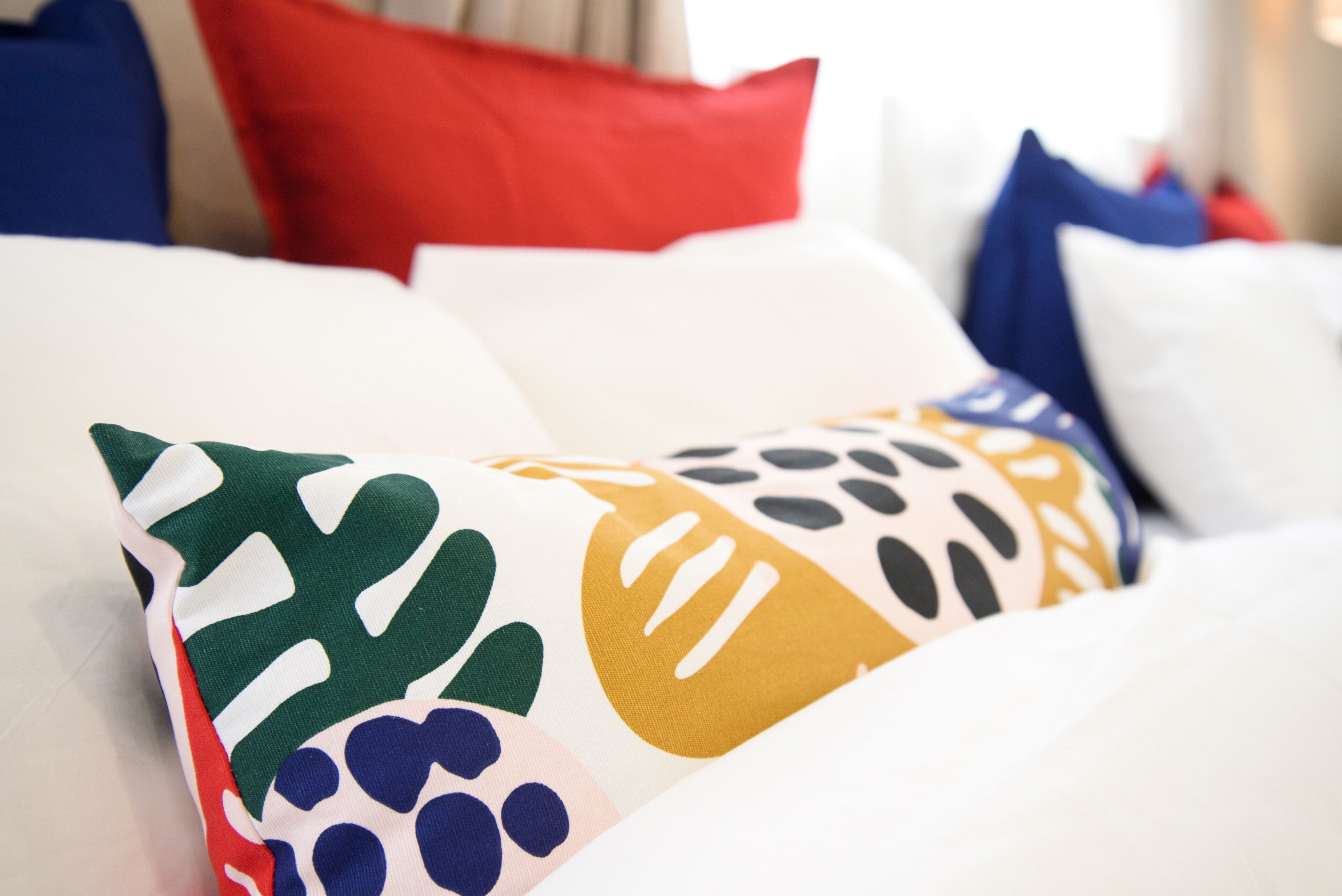 Ein Bett mit bunten Kissen und einem weißen Kopfteil.