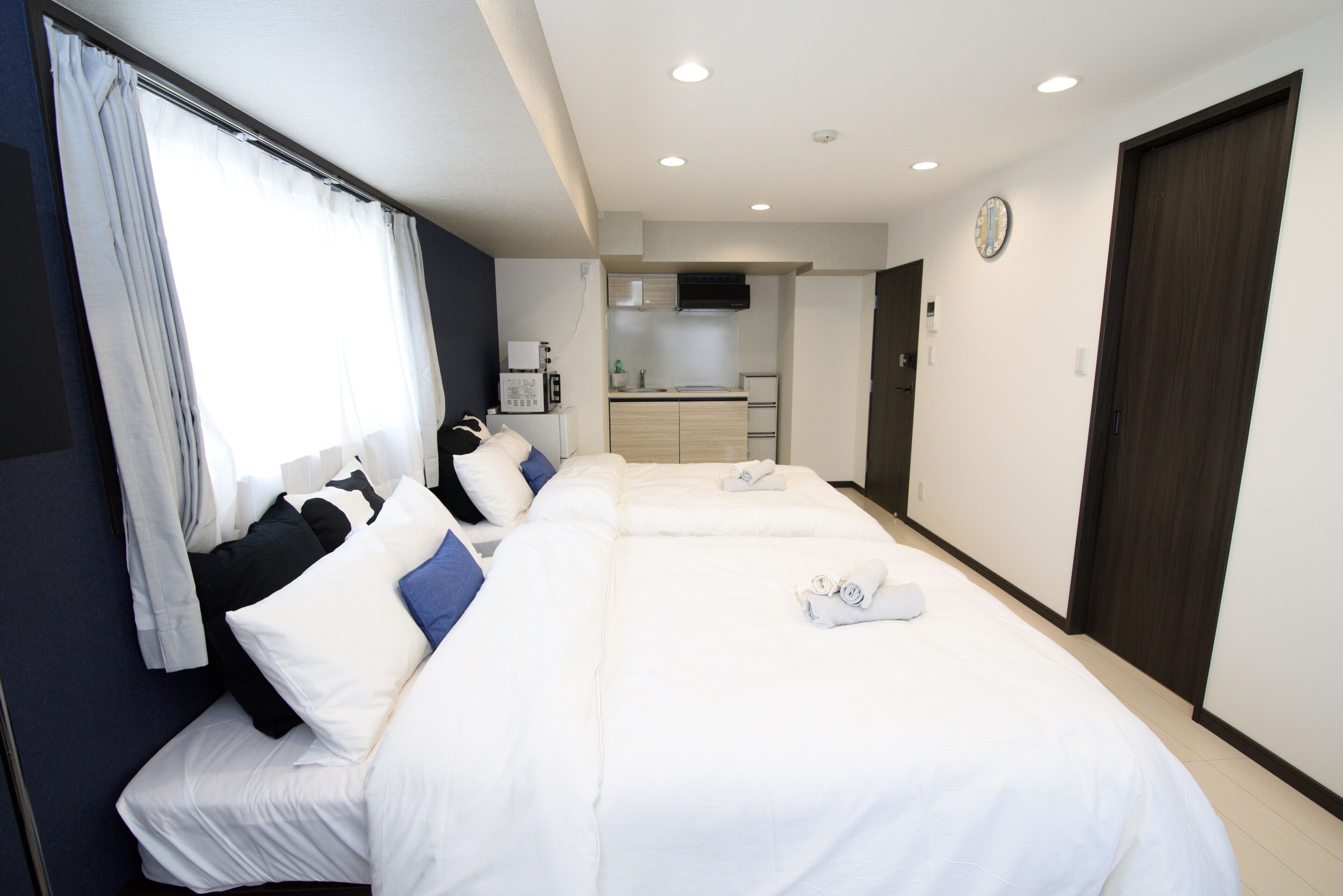 Una habitación de hotel con una cama grande, un kitchenette y un baño.