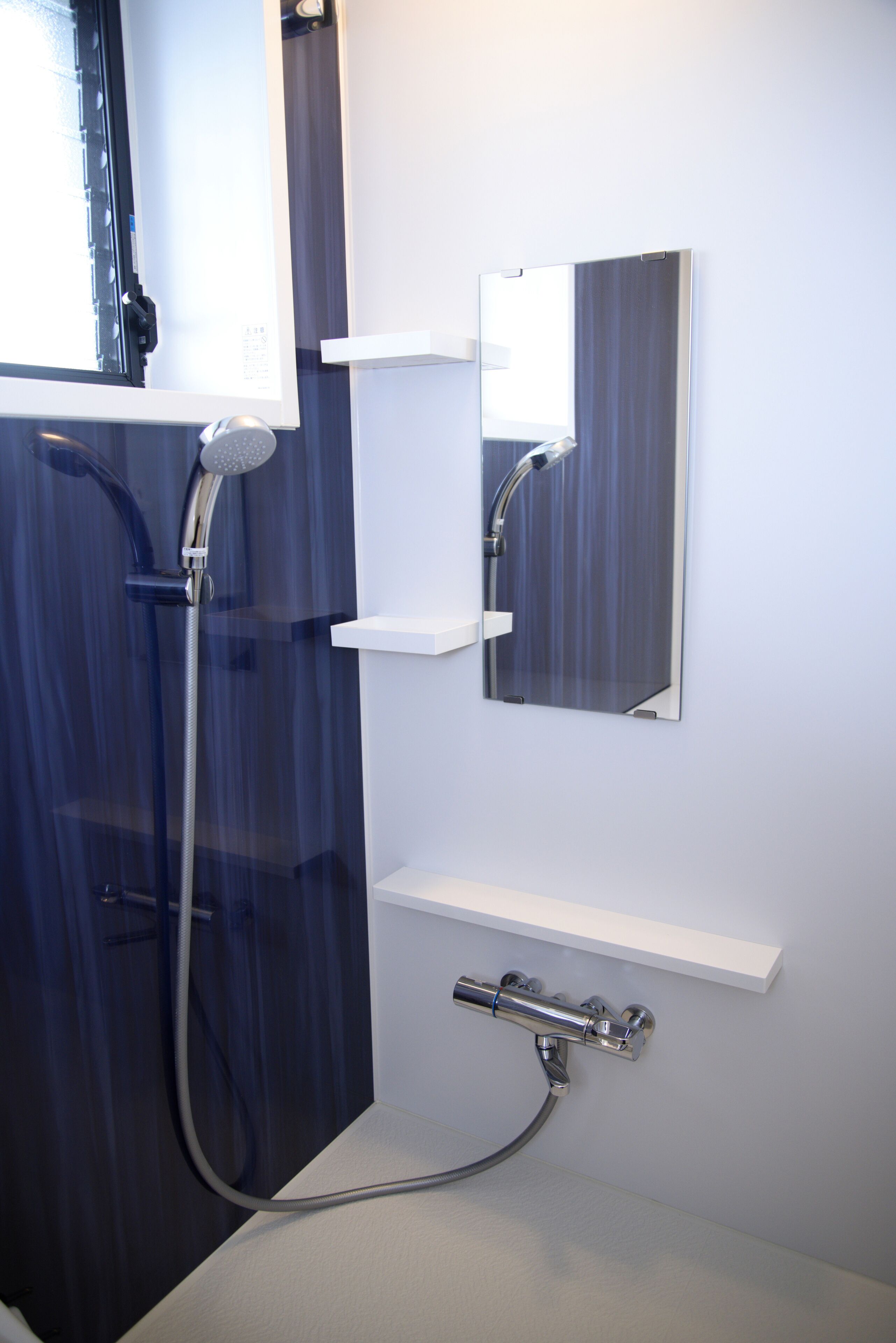 A bathroom with a shower, a mirror, and a sink.