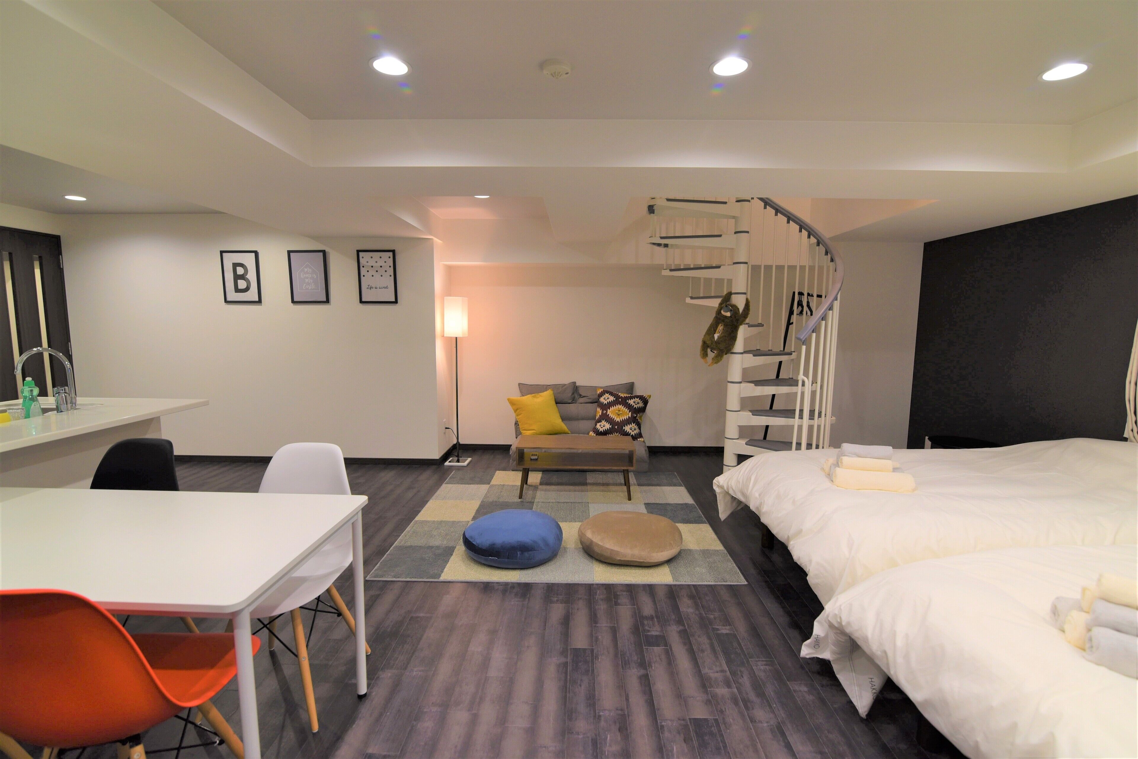 Ein modernes Hotelzimmer mit Schreibtisch, zwei Sessel, einer Couch, einem Bett und einer Wendeltreppe.