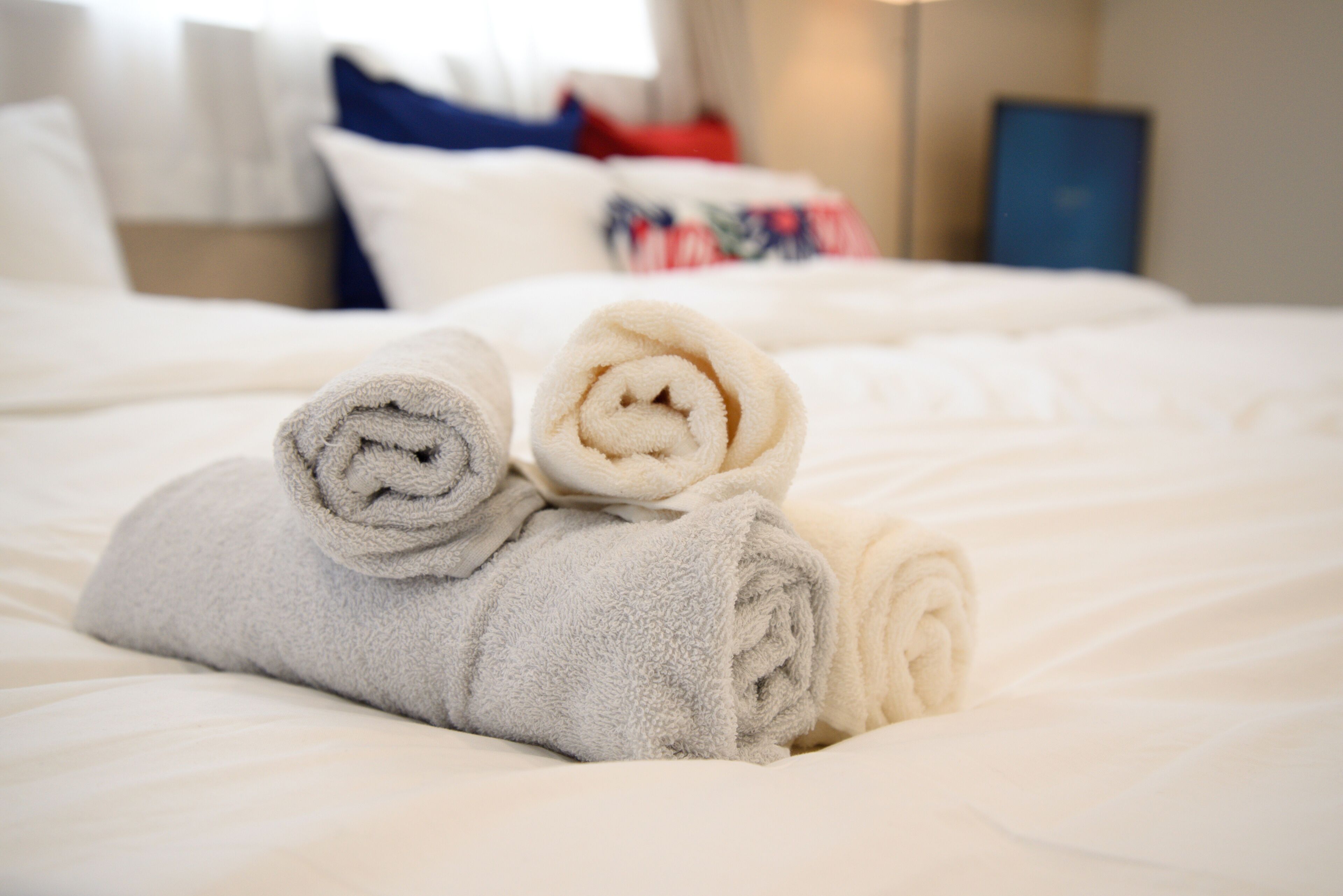 A neatly made bed with rolled towels and a pillow in a hotel room.