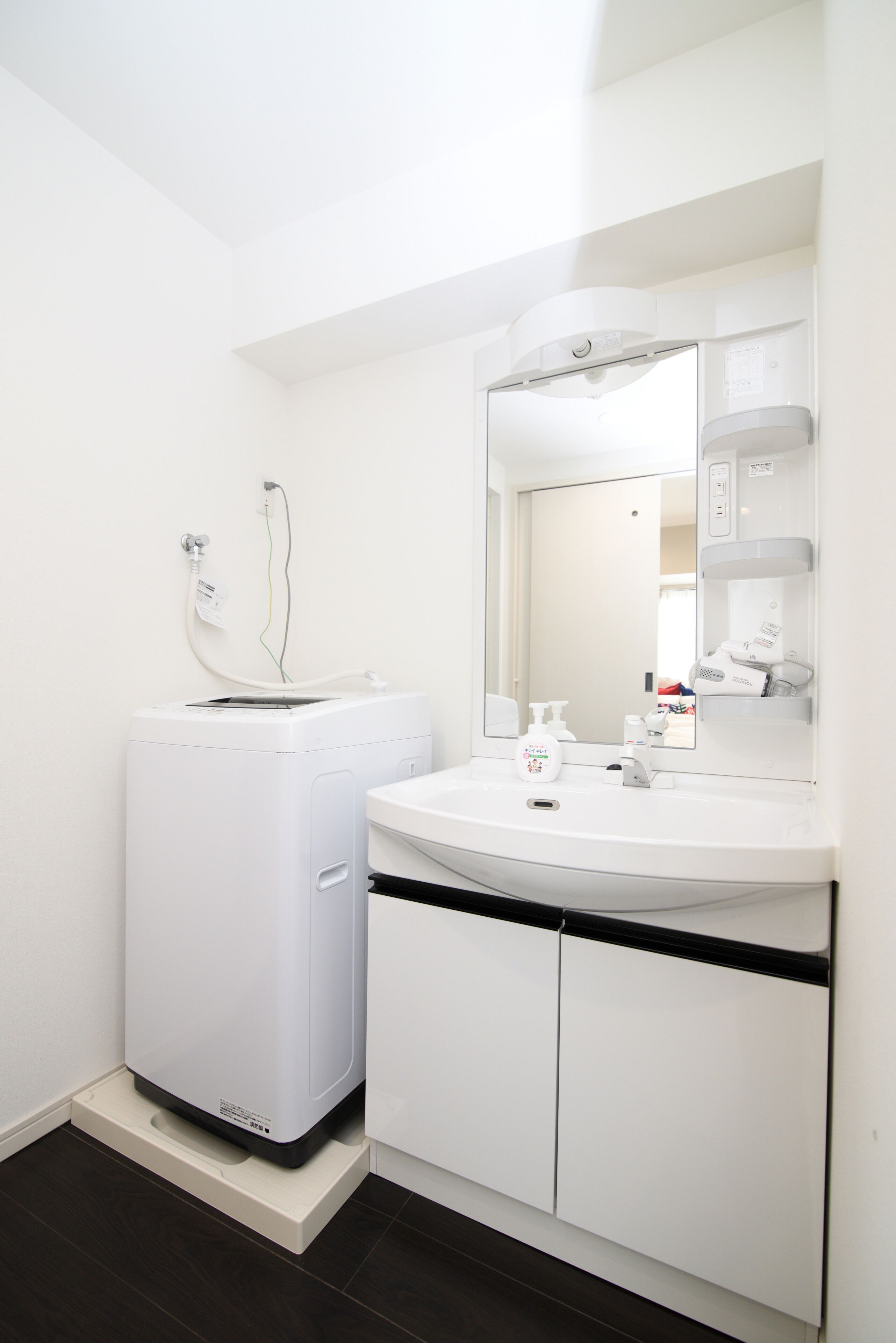 Un baño moderno con lavadora incorporada, un lavabo y un espejo.