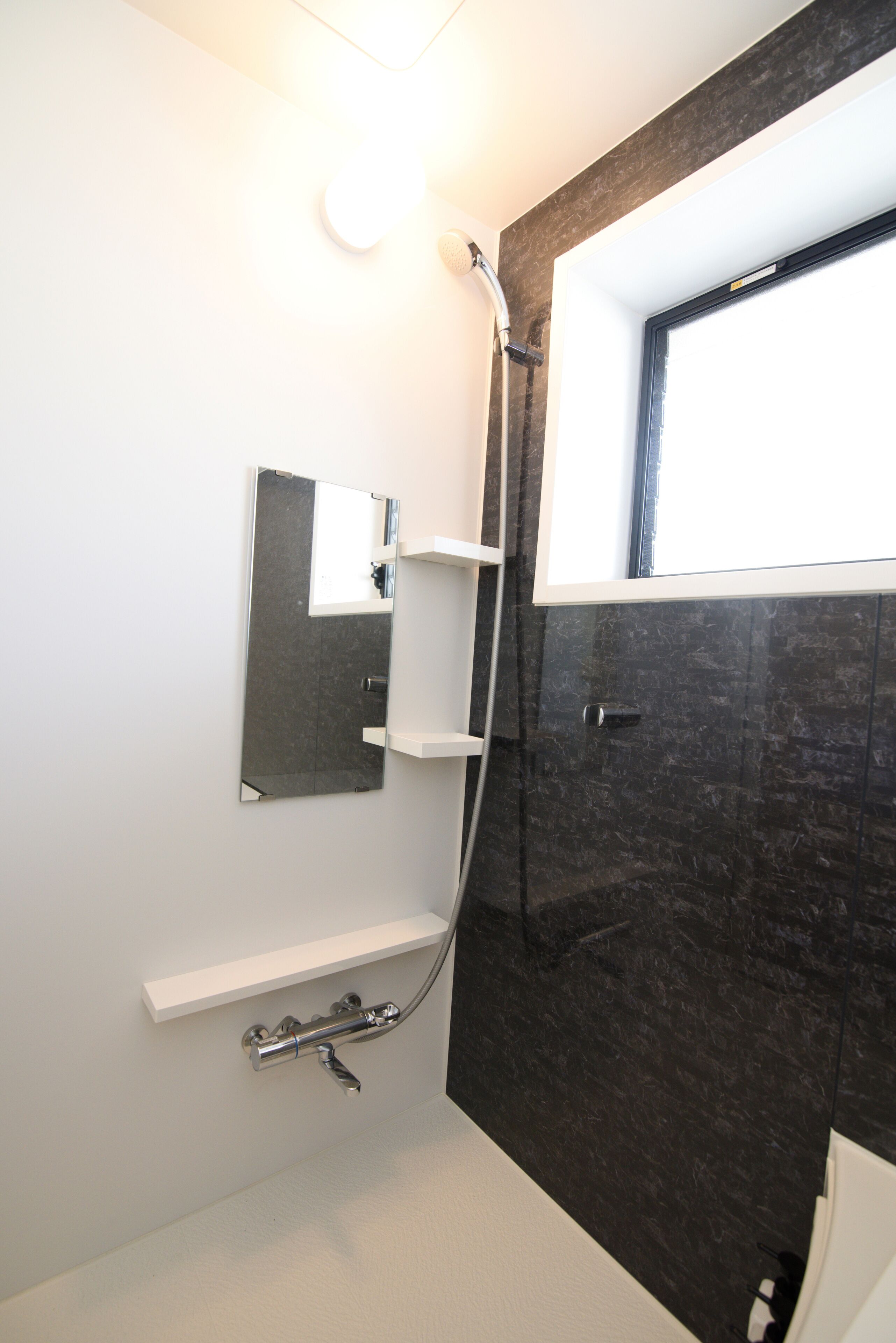 A modern bathroom with a shower, a mirror, and a window.