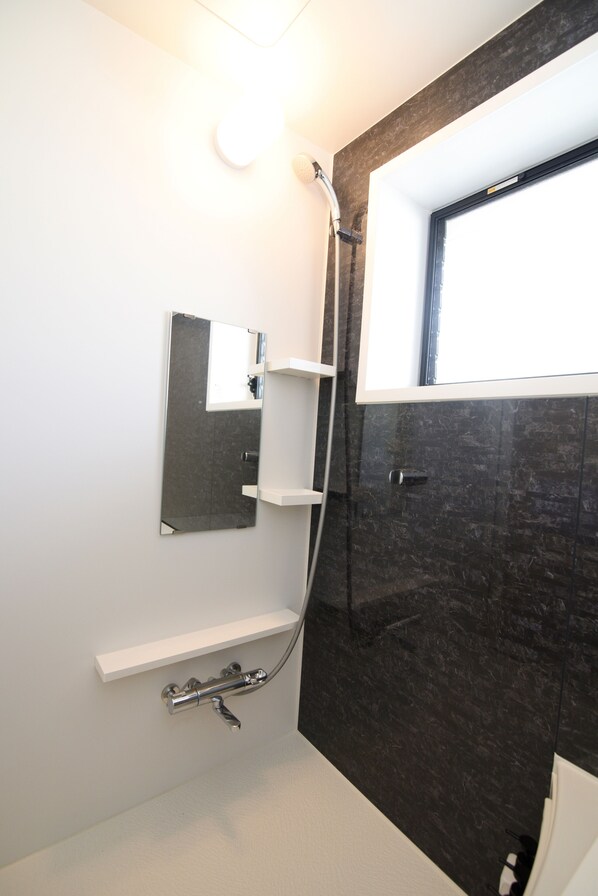 Un baño moderno con ducha, espejo y ventana.