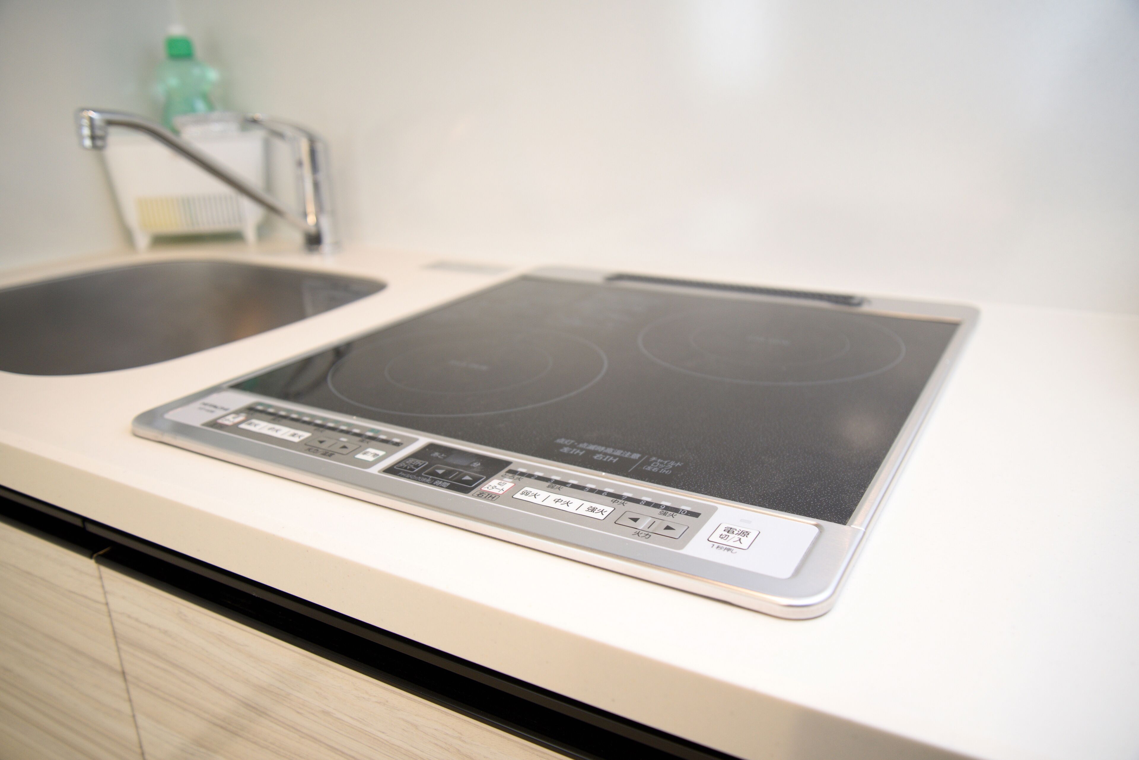 A kitchen with a built-in induction cooktop and a stainless steel sink.