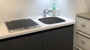 A modern kitchen with a built-in stove, a sink, and a trash bin. - Hotel Central Yokohama (Yokohama)