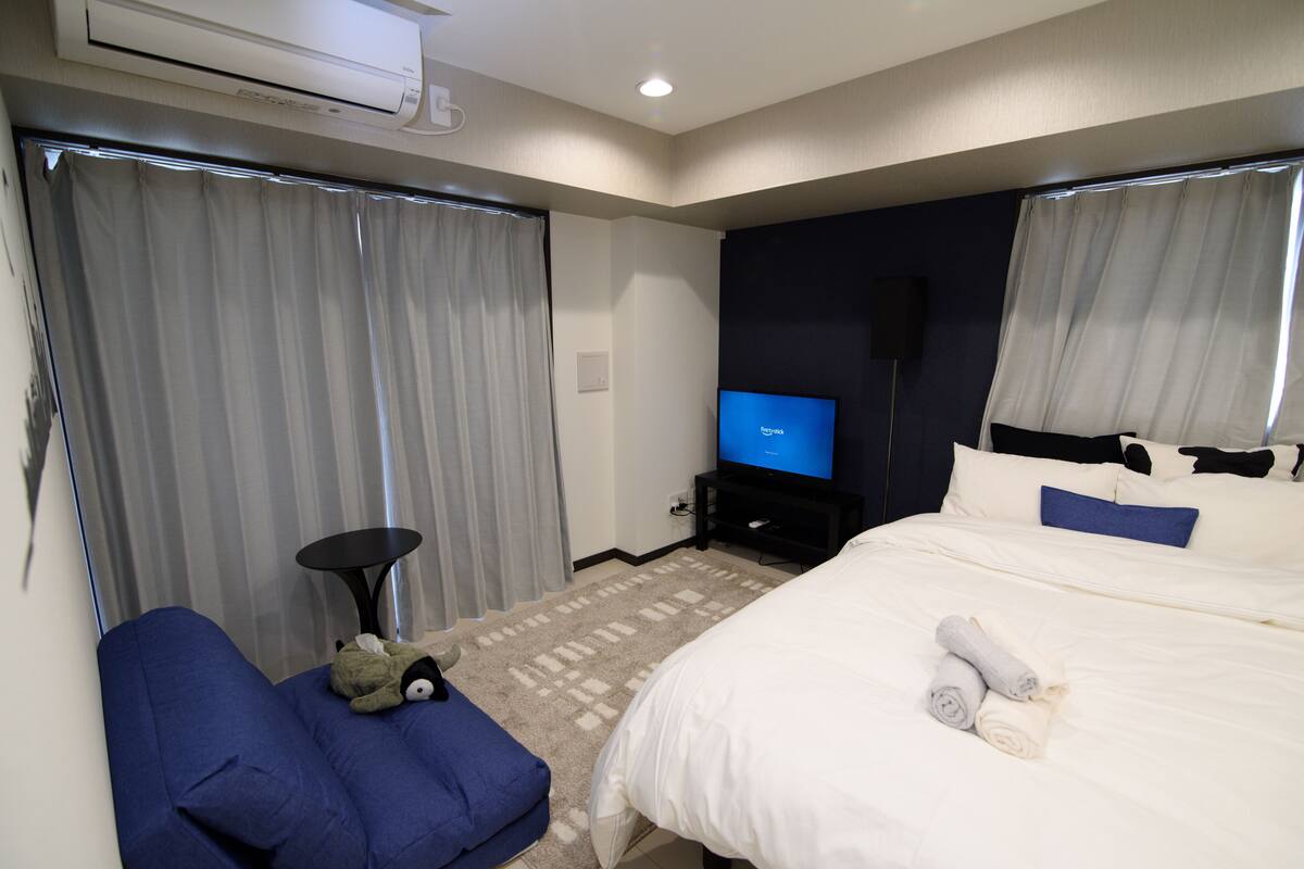 Ein Hotelzimmer mit Bett, Fernseher, kleinem Tisch und einer Couch.