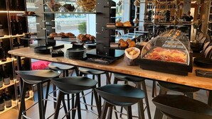 A café with a long counter, black stools, and a display case with pastries. - Hotel Pontemare (Palermo)