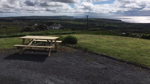 A picnic table in a rural setting with a view of a coastal landscape. - Atlantic Rose Cottage (Lisdoonvarna)