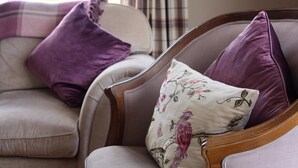 A living room with a sofa and armchair, a plaid curtain, and a window. - Atlantic Rose Cottage (Lisdoonvarna)