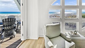 A room with a view of the beach, a grey sofa, and a table with decorative items. - "Views from Above" | Beachfront | Community Heated Pool (Panama City Beach)