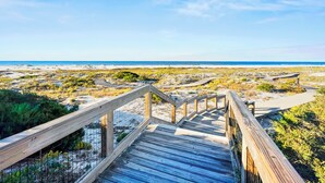 A wooden boardwalk leading to a beach with a clear sky. - "Views from Above" | Beachfront | Community Heated Pool (Panama City Beach)