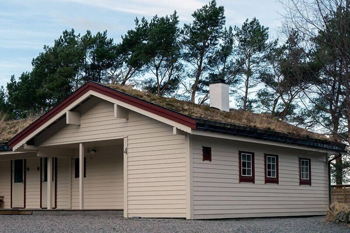 A single-story building with a sloped roof, a chimney, and a covered porch area.