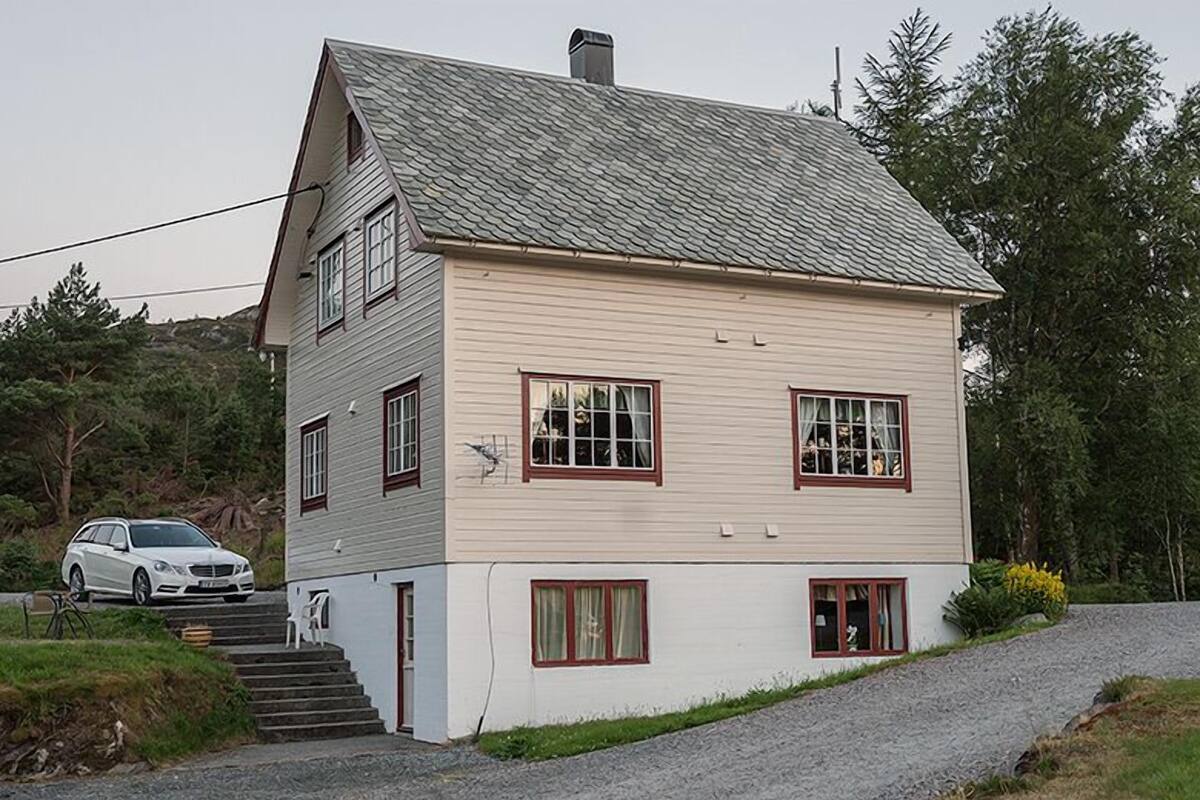 A two-story house with a sloped roof, a garage, and a driveway leading to the entrance.