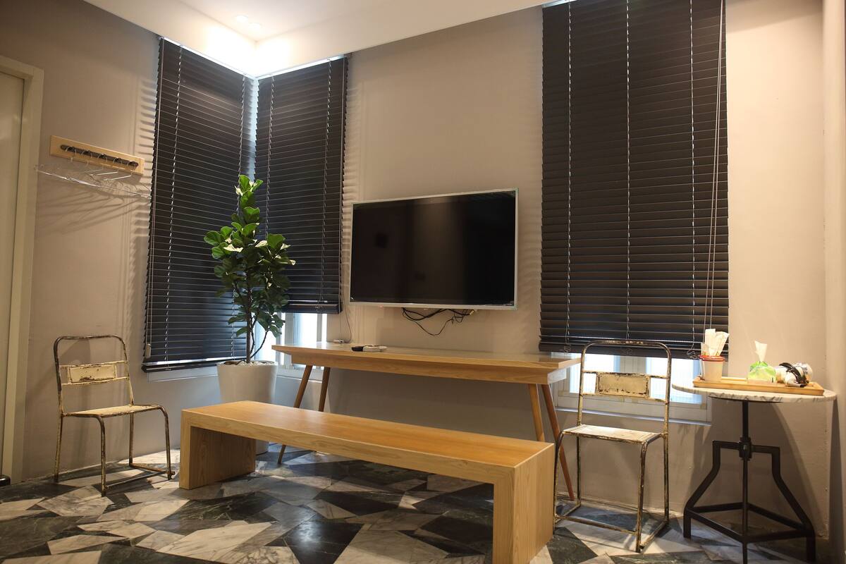 Una habitación con un banco de madera, un televisor montado en la pared y una planta en maceta.
