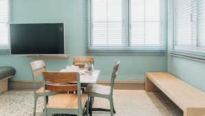 Un aula con una pizarra grande, sillas de madera, una mesa y un banco.