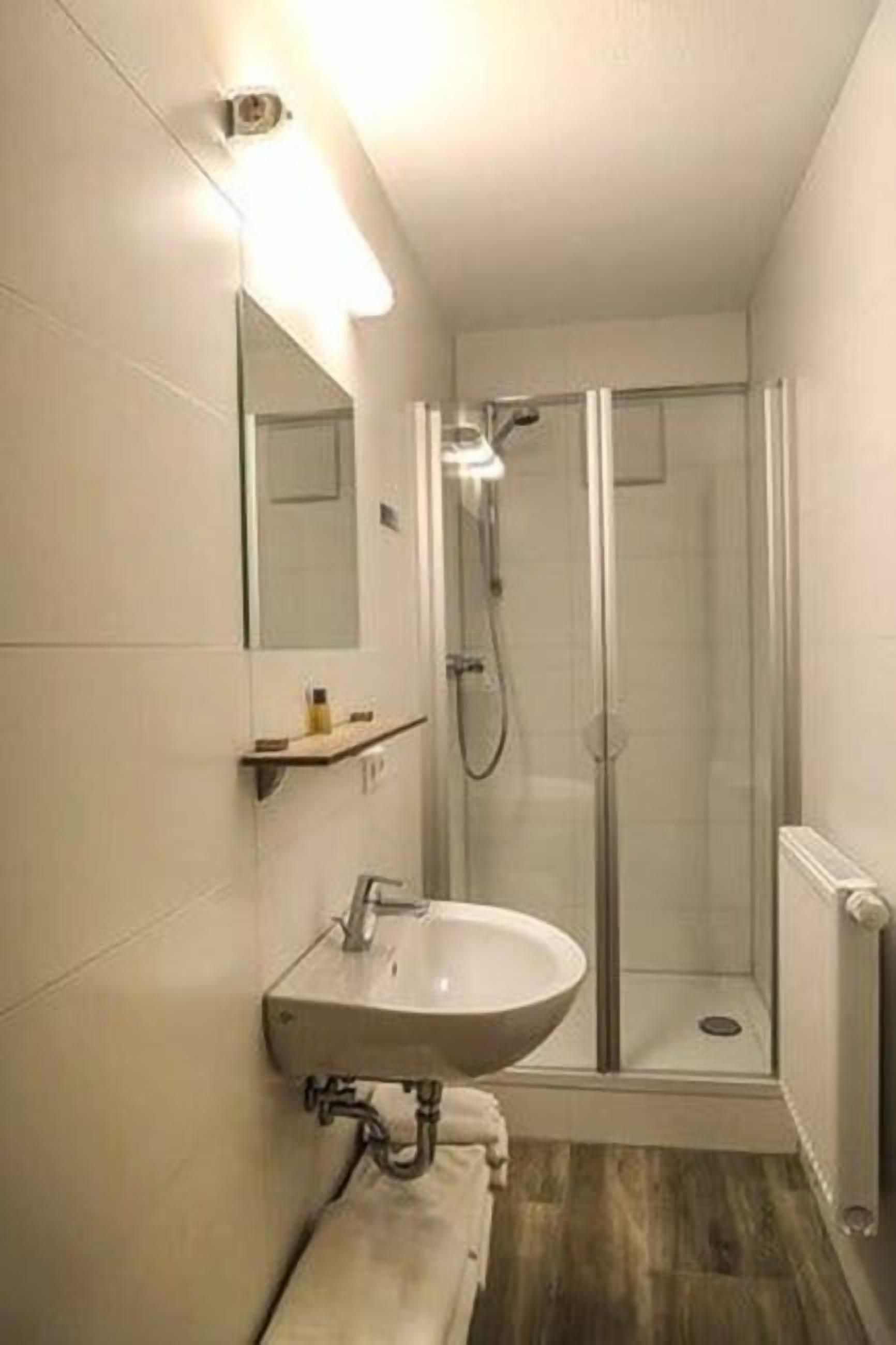 A bathroom with a glass-enclosed shower, a sink with a mirror, and a towel rack.