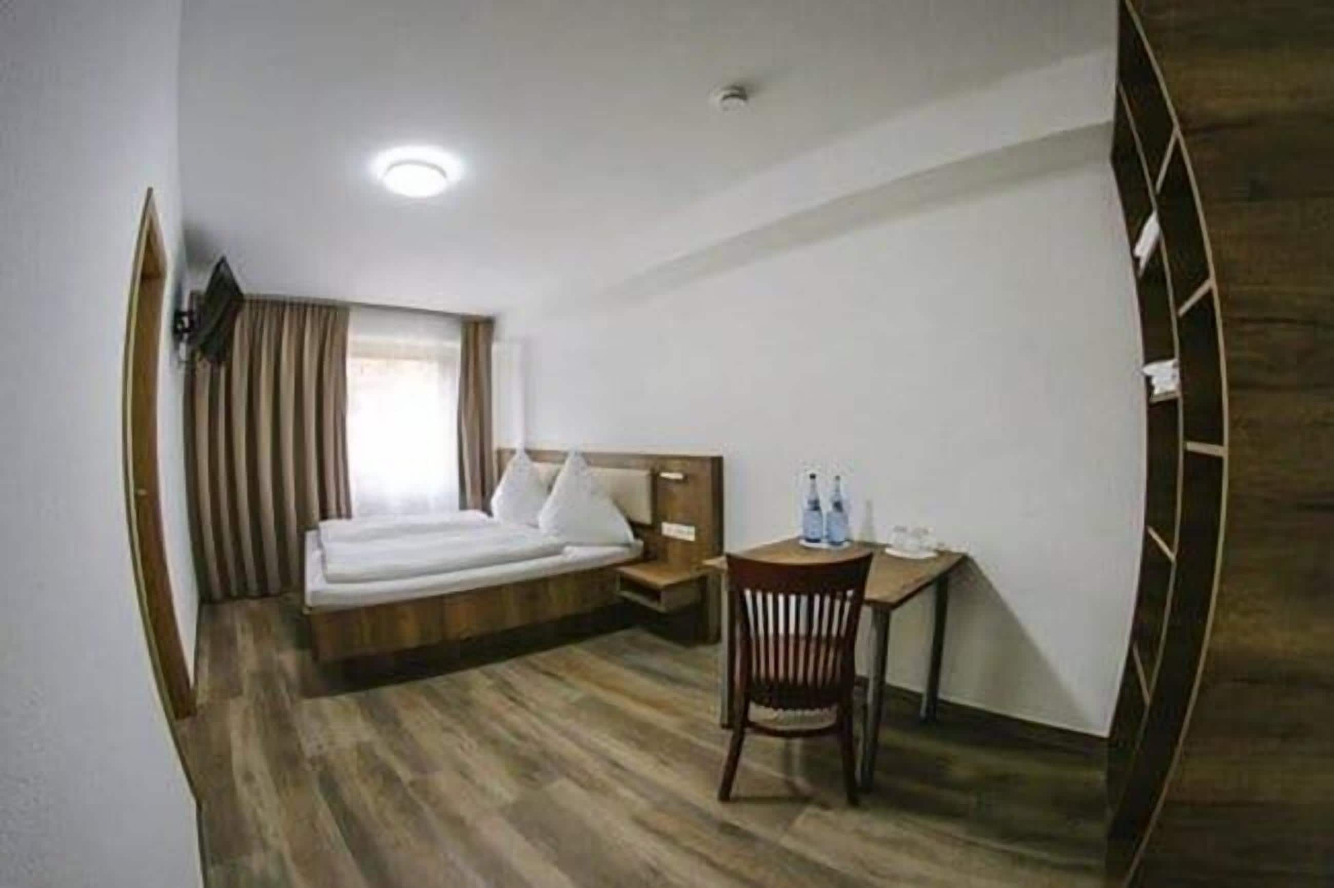 Una habitación de hotel con una cama, un escritorio y una silla.