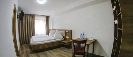 Una habitación de hotel con una cama, un escritorio y una silla.