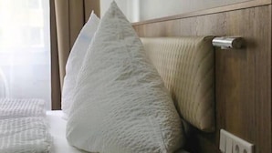 A hotel room with a bed, a wooden headboard, and a wall socket. - LOOK Hotel & Rooms (Crailsheim)