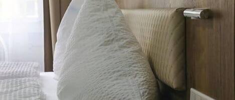Een hotelkamer met een bed, een houten hoofdeinde en een stopcontact.