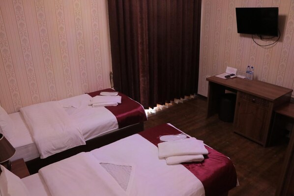 A hotel room with two beds, a desk, a television, and a wardrobe.