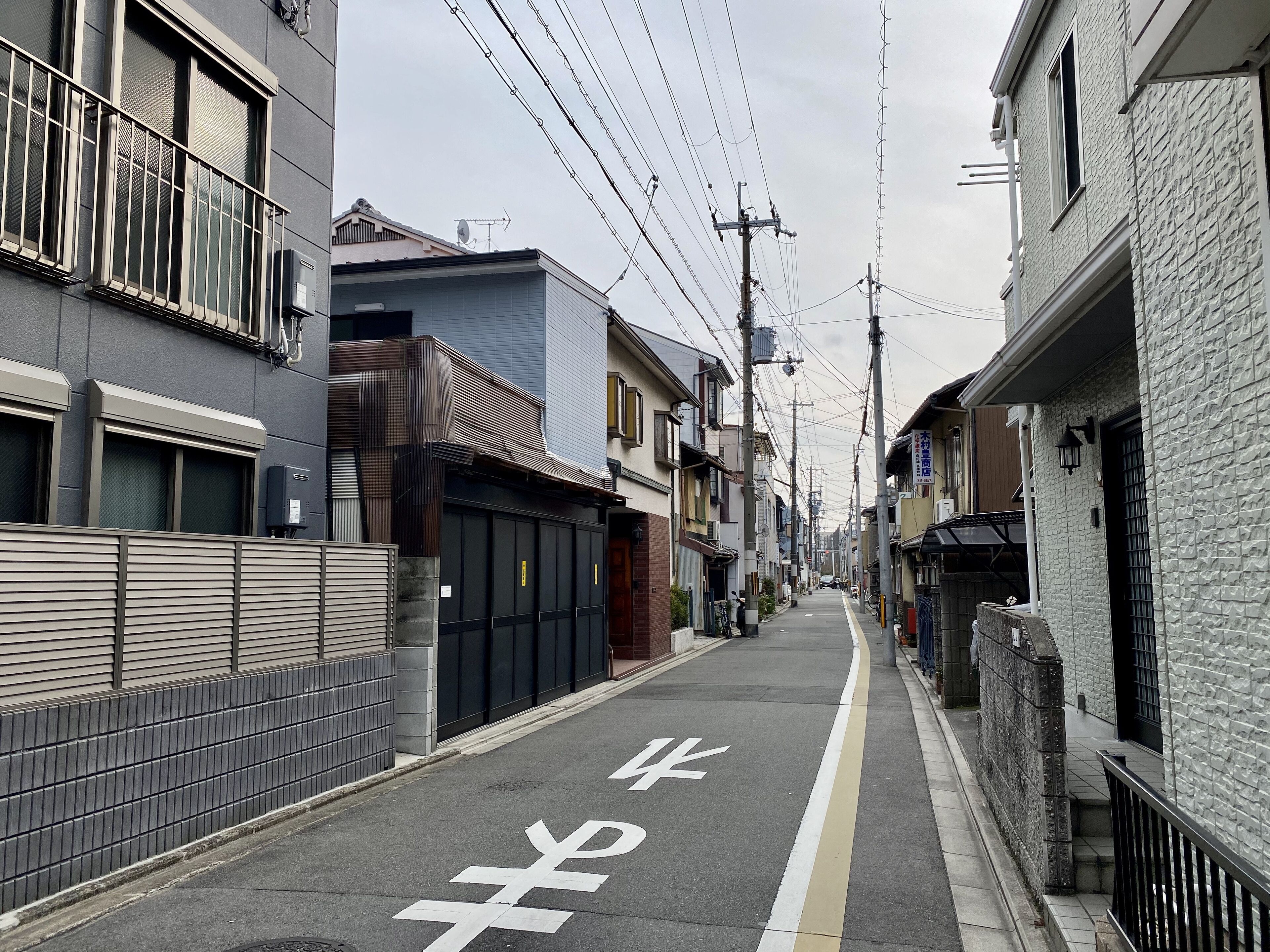 Una calle urbana estrecha bordeada de edificios residenciales, con un carril bici y postes de servicios públicos.