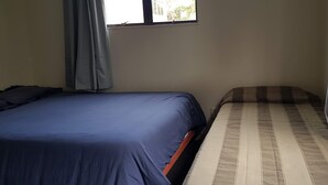 A room with a bed on the left and a smaller bed on the right.