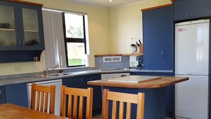 A compact kitchen with a dining area, featuring a wooden table and chairs, a built-in island, and a refrigerator.
