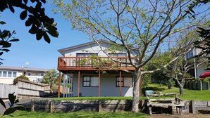 A two-story house with a balcony, surrounded by a well-maintained lawn and a wooden fence.