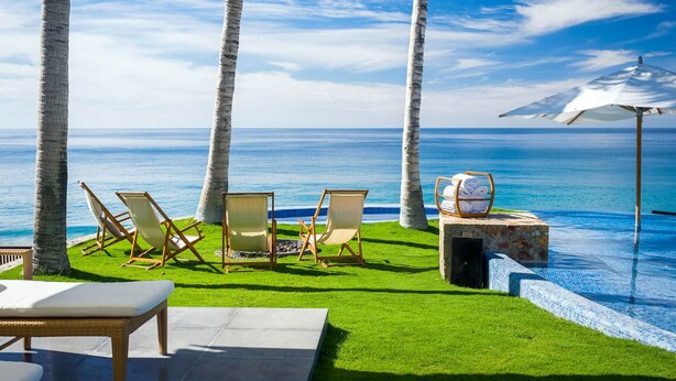 A poolside area with lounge chairs, a table with towels, and a view of the ocean. - Casa Oliver (San José del Cabo)