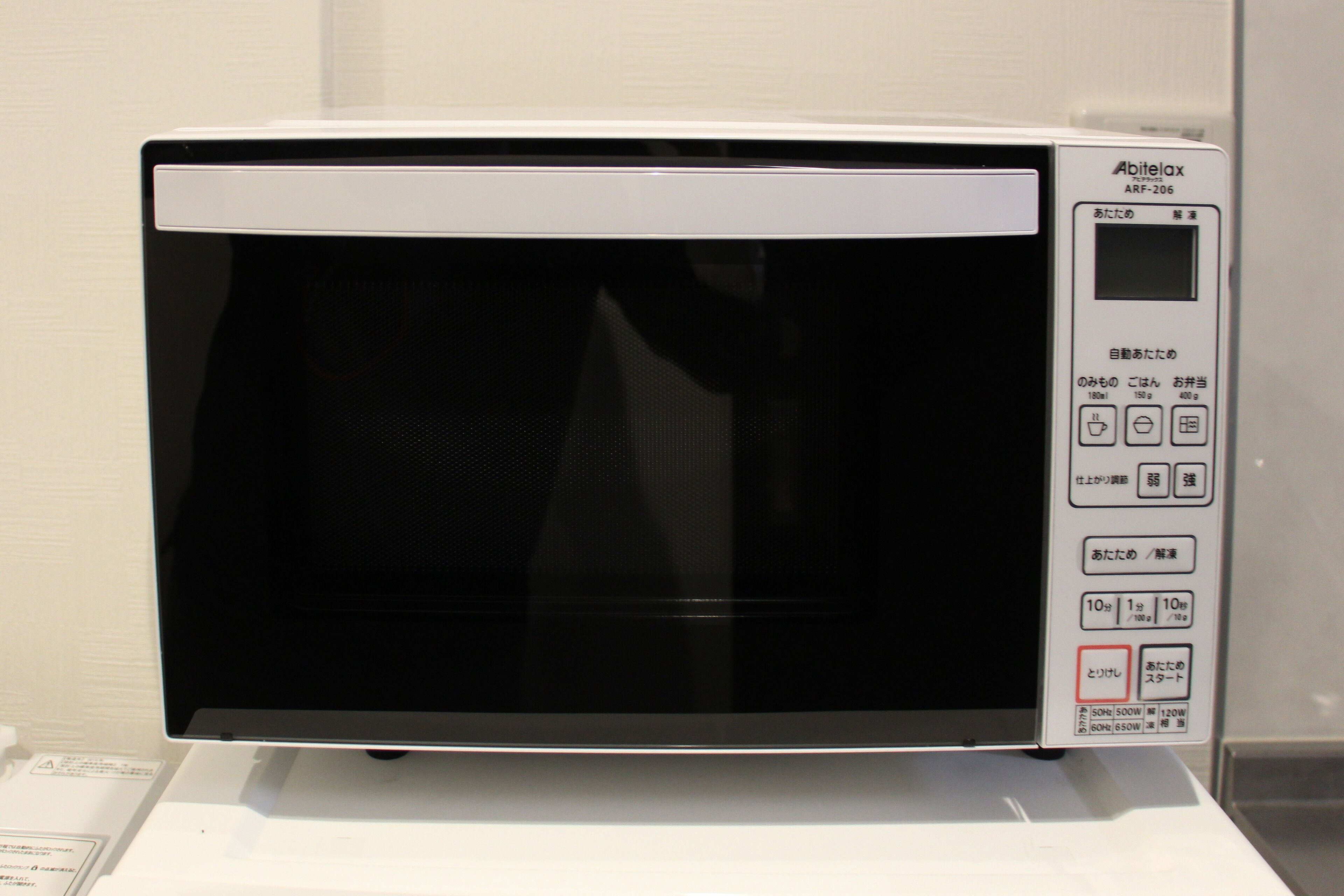 A white microwave oven with a digital display and control panel, placed on a white surface.